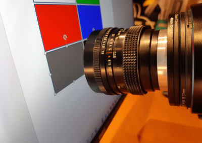 Ein Festbrennweitenobjektiv Zeiss Pancolar 1.8/50 ist in Retrostellung an einem Sony Teleobjektiv 70300 befestigt, um LCD-Bildpunkte einer Graufläche auf einem LCD-Monitor zu fotografieren.